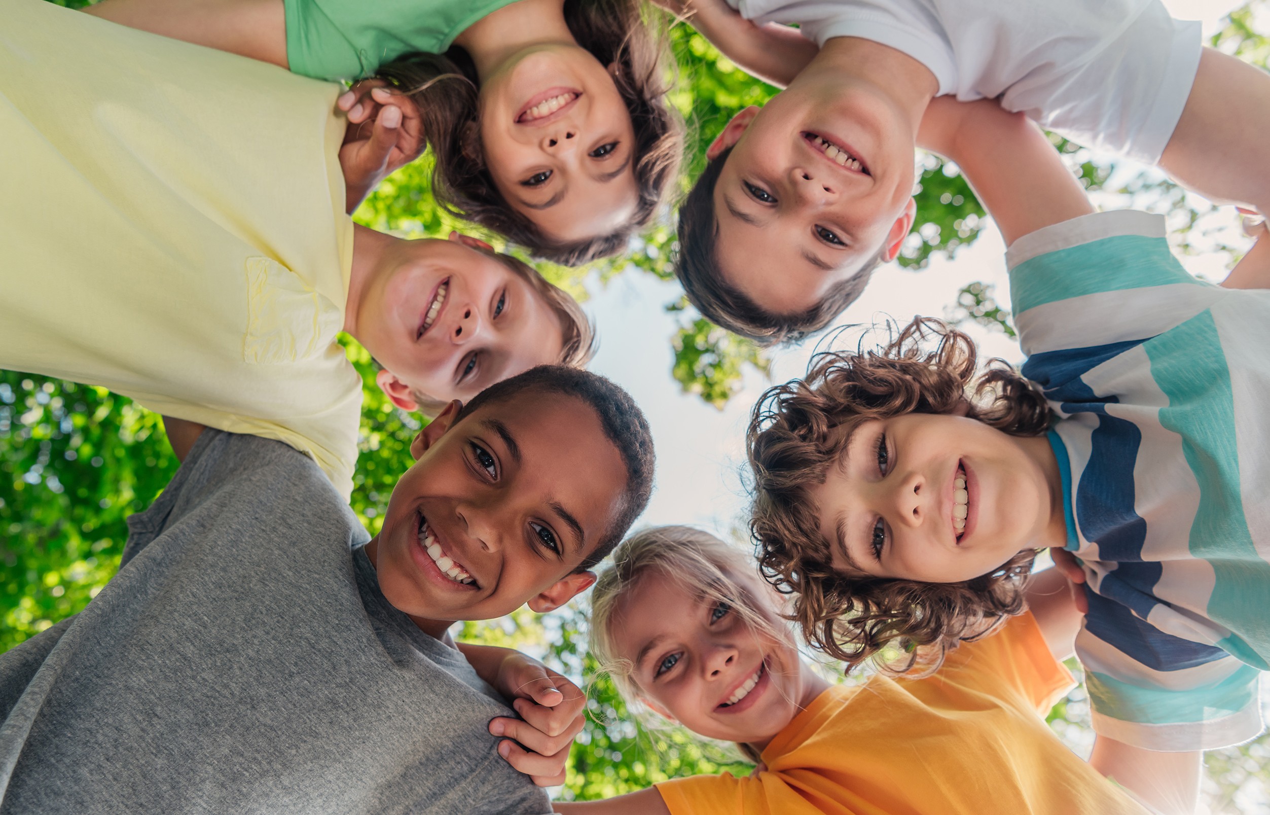 bottom view of cheerful multicultural children looking at camera in park